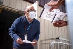 FILE - An employee of the Philadelphia Commissioners Office examines ballots at a satellite election office at Overbrook High School in Philadelphia, Oct. 1, 2020.