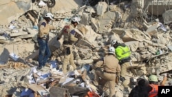 FILE - Civil defense members search for survivors at a site hit yesterday by what activists said were airstrikes carried out by the Russian air force in Idlib city, Syria, Dec. 21, 2015. 