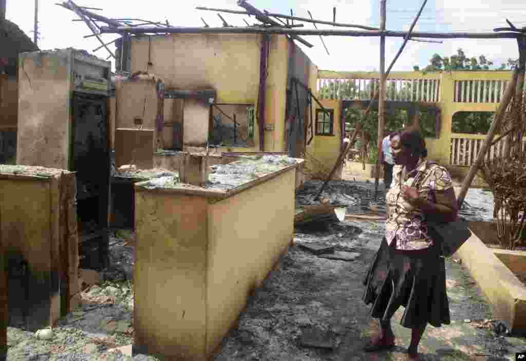 A woman observes the remains of the Breeze View Hotel, where residents watching the World Cup soccer tournament were attacked and killed by militants, Mpeketoni, Kenya, June 16, 2014.