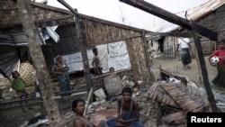 Rohingya people pass their time in a damaged shelter in Rohingya IDP camp outside Sittwe, Rakhine state on August 4, 2015