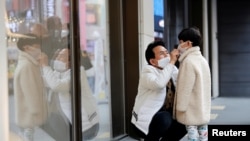 A man and a boy wear masks to prevent contracting a new coronavirus at Myeongdong shopping district in Seoul, South Korea, Feb. 20, 2020. 