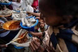 FILE - A young boy looks up as displaced Tigrayans line up to receive food at a reception center for the internally displaced in Mekele, in the Tigray region of northern Ethiopia, May 9, 2021.