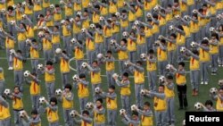 FILE - Students do morning exercises with soccer balls on a playground at a primary school in Linhai, Zhejiang province, March 26, 2015.