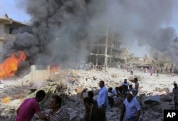 In this photo released by the Syrian official news agency SANA, Syrians gather at the scene where twin bombings struck Kurdish town of Qamishli, Syria, July 27, 2016.