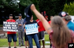 A rally-goer shouts as she passes protesters before Republican presidential candidate Donald Trump speaks at a rally in Dimondale, Mich. Aug. 19, 2016.
