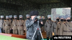 North Korean leader Kim Jong Un uses binoculars while attending a drill by a unit of the Korean People's Army, Feb. 29, 2020.