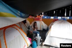 A woman looks at her mobile phone next to her tent in a provincial campsite on a basketball court after her flat was affected by the the earthquake in Mexico City, Mexico, Sept. 25, 2017.
