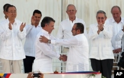 Colombia’s President Juan Manuel Santos, front left, and the top commander of the Revolutionary Armed Forces of Colombia (FARC) Rodrigo Londono, known by the alias Timochenko, shake hands after signing the peace agreement between Colombia’s government and the FARC to end over 50 years of conflict in Cartagena, Colombia, Sept. 26, 2016.