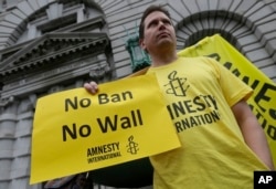 William Butkus of Amnesty International holds up a sign outside of the 9th U.S. Circuit Court of Appeals in San Francisco, Feb. 7, 2017.