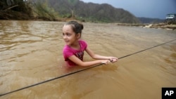 Ruby Rodriguez, de ocho años, cruza el río San Lorenzo Morovis con el agua a la cintura debido a la caída del puente destruido durante el paso del huracán María.