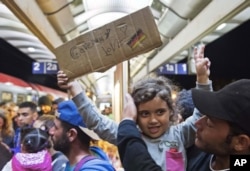 A migrant girl holds a sign expressing her love to Germany as she arrives at the train station in Saalfeld, central Germany, Sept. 5, 2015.