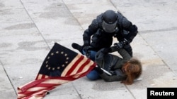 Seorang petugas polisi menahan seorang pengunjuk rasa pro-Trump ketika massa menyerbu Capitol AS, selama rapat umum untuk memperebutkan sertifikasi hasil pemilihan presiden AS 2020 oleh Kongres AS, di Gedung Capitol AS di Washington. (Foto: Reuters)