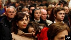 A Catholic worshiper carries her daughter as Archbishop Pizzaballa (not seen), apostolic administrator of the Latin Patriarch of Jerusalem, leads the Christmas Midnight Mass in Saint Catherine's Church at the Church of the Nativity, Dec. 25, 2016.
