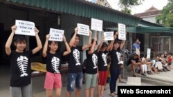 FILE - Protesters hold signs about the mass fish deaths in Nghe An Province, central Vietnam. Protests Sunday led to dozens of people being detained by police in Hanoi and Ho Chi Minh City.