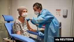 A woman receives a vaccination against the COVID-19 at a temporary vaccination center in Lodz, Poland, Jan. 25, 2021. 