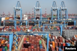 A cargo ship is seen behind containers at an automated container terminal in Qingdao port, Shandong province, China, Oct. 1, 2018.
