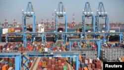 A cargo ship is seen behind containers at an automated container terminal in Qingdao port, Shandong province, China, Oct. 1, 2018.