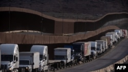 Trucks queue next to the border wall before crossing to the United States at Otay commercial port in Tijuana, Baja California state, Mexico, on Jan. 22, 2025. 