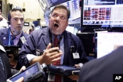 Trader John Santiago, center, works on the floor of the New York Stock Exchange, Aug. 24, 2015.