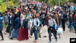 Migrants walk along a street after they arrived by train in Hegyeshalom, at the Austrian border, 169 km west of Budapest, Hungary, Oct. 7, 2015.
