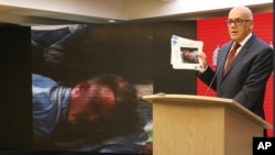 FILE - In this Venezuelan Communications Ministry photo, Communications Minister Jorge Rodriguez shows a photograph of a man he identifies as former U.S. special forces soldier Luke Denman, taken in Venezuela during his arrest, in Caracas, May 5, 2020.