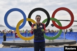 Triathlete Gwen Jorgensen of the United States poses with her gold medal at the 2016 Summer Olympics in Rio de Janeiro, Aug. 20, 2016.