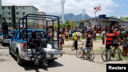 Des habitants regardent un policier passé lors d'une opération anti-drogues dans la favela de la Cité de Dieu à Rio de Janeiro, Brésil, le 20 novembre 2016