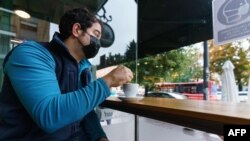 A man wearing a face mask sits at a coffee shop in Burgos, northern Spain, on Oct. 21, 2020, on the first day of a two-week lockdown in an attempt to limit the contagion of the new coronavirus in the area.
