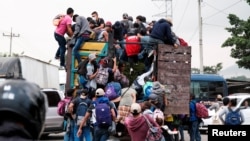 Hondurans climb onto the back of a truck for a ride in a new caravan of migrants, set to head to the United States, in Cofradia, Honduras January 15, 2021.