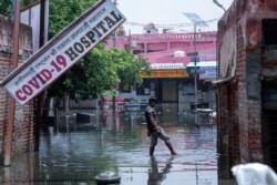 Seorang pria berjalan di jalan yang digenangi banjir usai hujan deras di rumah sakit khusus COVID-19 di Ghaziabad, pinggiran Ibu Kota India, New Delhi, 23 Mei 2021.