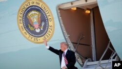 President Donald Trump waves during his arrival on Air Force One at Miami International Airport in Miami, April 16, 2018. 