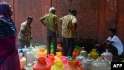 Indian residents stand around with plastic pots filled with drinking water at a distribution point in Chennai on June 19, 2019. (Photo by ARUN SANKAR / AFP)