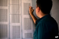 Bahzad Farhan Murad points to a list of missing and killed Yazidis to The Associated Press in the small office where he collects evidence on Islamic State crimes against Yazidis, in Dohuk, Iraq, May 22, 2016.