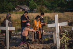 Anggota keluarga memberikan penghormatan terakhir saat pemakaman orang terkasih yang meninggal karena COVID-19 di sebuah pemakaman di Surabaya pada 9 Agustus 2021. (Foto: AFP/Juni Kriswanto)
