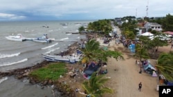 Migrantes se reúnen el 13 de octubre de 2022 en Necoclí, Colombia, un punto de parada para los migrantes que toman embarcaciones hacia Acandí, una localidad que conduce a la selva del Tapón del Darién. 