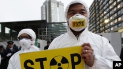 A Greenpeace activist holds a placard during a demonstration outside Japan's Prime Minister Yoshihiko Noda's official residence in Tokyo, criticizing the government's declaration of cold shutdown at the Fukushima nuclear power plant December 16, 2011.