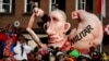 A carnival float with a caricature of Russian President Vladimir Putin moves past revelers during a carnival parade in Dusseldorf, Germany, Feb. 16, 2015. The text on the right arm reads "military;" the text on its left arm - "economy."