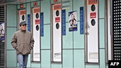 FILE - A man walks past public toilets in Shanghai during the World Toilet Day, Nov. 19, 2009.