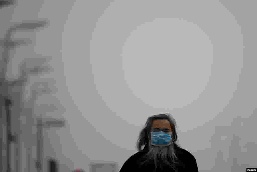 A man wearing a mask makes his way amid thick haze in Beijing, Feb. 25, 2014.&nbsp;