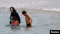 FILE - A Muslim woman wears a burkini, a swimsuit that leaves only the face, hands and feet exposed, on a beach in Marseille, France, Aug. 17, 2016.