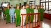 Doan Van Vuon (standing, 4th L), Doan Van Quy (standing, 2nd L) and Doan Van Sinh (standing, 3rd R) stand with policemen in front of the dock at a court during a verdict session in Hai Phong, April 5, 2013.