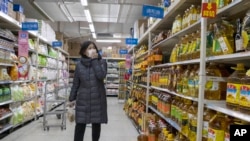 A shopper wearing a face mask browses an aisle of cooking oil in a supermarket in Beijing on Monday, March 16, 2020.
