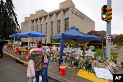 A woman and her children pause, Nov. 3, 2018, to take in a makeshift memorial outside the Tree of Life synagogue honoring the 11 people killed, Oct 27, 2018, while worshipping, in the Squirrel Hill neighborhood of Pittsburgh.