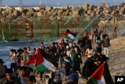 Protesters run to take cover from teargas fired by Israeli troops near the fence of the Gaza Strip border with Israel during a protest on the beach near Beit Lahiya, northern Gaza Strip, Nov. 19, 2018.