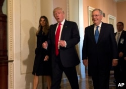 FILE - President-elect Donald Trump, accompanied by his wife Melania, and Senate Majority Leader Mitch McConnell of Ky., gestures while walking on Capitol Hill in Washington, November 10, 2016.