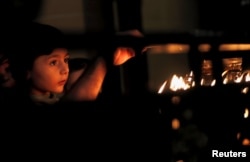 An Armenian Christian boy lights a candle during a Sunday mass at the main Armenian Orthodox Church in Cairo, Egypt, Sept. 16, 2018.