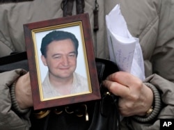 FILE - A portrait of lawyer Sergei Magnitsky, who died in jail, is held by his mother, Nataliya Magnitskaya, as she speaks during an interview with the AP in Moscow, Nov. 30, 2009.