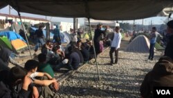 Protesters sit on the train tracks, keeping the trains from going from Greece to Macedonia in Idomeni, Greece, March 30, 2016. (H. Murdock/VOA)