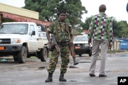 FILE - A Burundian soldier with his gun and rocket launcher guard a deserted street in Bujumbura, Burundi, Nov. 8, 2015.