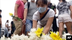 Residents of the Harbour City apartment complex place flowers at a memorial near their building for victims of the Tianjin blasts in northeastern China's Tianjin municipality, Aug. 18, 2015.